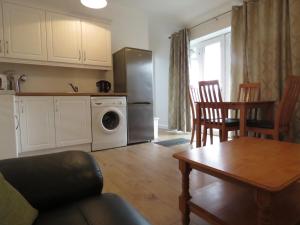 a kitchen and living room with a table and a refrigerator at The Lodge guesthouse in Brittas