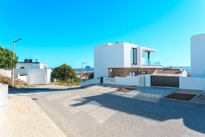 een wit huis met de oceaan op de achtergrond bij Villa view bay with Jacuzzi in Salir de Porto