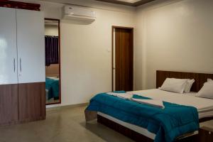 a bedroom with a bed with a blue blanket on it at Ambika Hills Resort in Junnar +8 photos