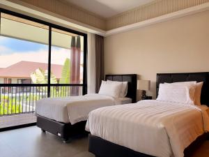 two beds in a bedroom with a large window at Villa Daun Emas in Jimbaran +19 photos