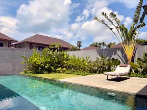 a chair sitting next to a swimming pool at Villa Daun Emas in Jimbaran