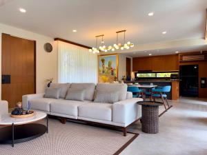 a living room with a white couch and a kitchen at Villa Daun Emas in Jimbaran