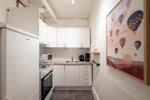 a small kitchen with white cabinets and a refrigerator at Lovely City Apartments in Vibrant Area of Copenhagen in Copenhagen