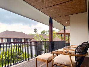 a patio with two chairs and a table on a deck at Villa Daun Emas in Jimbaran