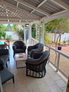 a screened in porch with chairs and a table at Charmante villa avec piscine proche plage in Flic-en-Flac