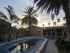 una piscina frente a una casa con palmeras en Vogelsang Guesthouse, en Omaruru