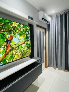 Que Self Catering Apartments - Block7 في غابورون: غرفة معيشة مع تلفزيون بشاشة مسطحة كبيرة على جدار +10 صور