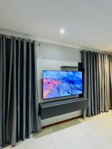Que Self Catering Apartments - Block7 في غابورون: تلفزيون بشاشة مسطحة في غرفة مع ستائر