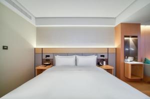 a bedroom with a large white bed and wooden cabinets at JI Hotel Hangzhou West Railway Station in Hangzhou