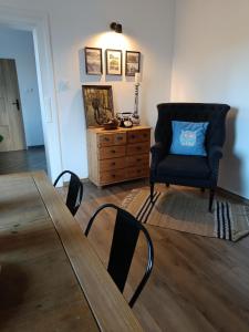 a living room with a table and a chair and a dresser at Apartament w Starej Szkole in Zagórze Śląskie