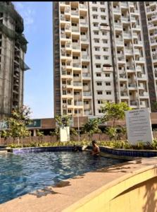 Un hombre en una piscina frente a un edificio alto. en Aesthetic Modern 2BHK Work & Relax Balcony Views, en Jāmb