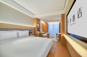 a hotel room with a bed and a flat screen tv at JI Hotel Hangzhou West Railway Station in Hangzhou