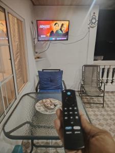 Casa Wili Taboga في تابوغا: شخص يحمل ريموت كنترول امام طاولة