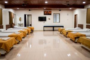 a room with rows of beds with a flat screen tv at Ambika Hills Resort in Junnar