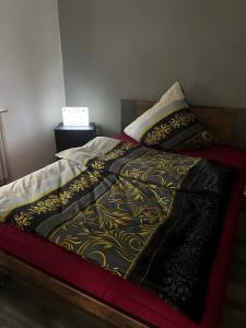 a bed with a black and gold blanket on it at Apartament in Bürstadt +19 photos