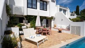 een villa met een zwembad en een patio met stoelen en een parasol bij Quinta do Lago, Victory Village N 63 in Almancil