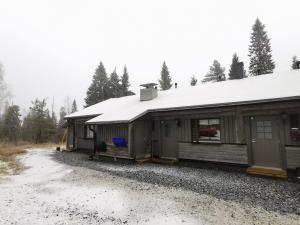 una baita con il tetto coperto di neve su una strada sterrata di Villa Aurora a Syöte