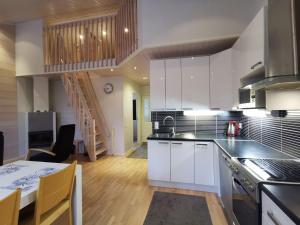 a kitchen with white cabinets and a dining table at Villa Aurora in Syöte