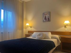 a bedroom with a blue bed with two pillows at Hotel Berna - Valdeorras - Camino de Invierno in La Rúa