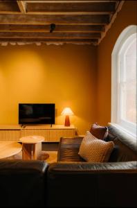 a living room with a couch and a flat screen tv at Gibson Mill waterfront warehouse apartment - 101 in Hobart