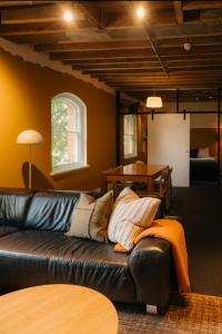a living room with a black leather couch and a table at Gibson Mill waterfront warehouse apartment - 101 in Hobart