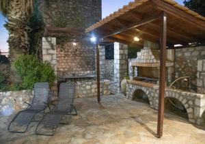 Kitta Mani Towerhouse - Mountain Views & Garden في Koíta: فناء مع كرسيين ومدفأة حجرية