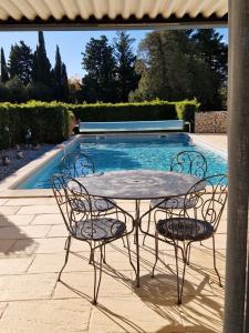 a table and chairs next to a swimming pool at Au bout du chemin Chez Tina in Sarrians