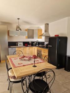 a kitchen with a table and a black refrigerator at Au bout du chemin Chez Tina in Sarrians