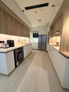 a large kitchen with white counters and a refrigerator at Excellence Apartment شقه التميز في المونسيه in Riyadh