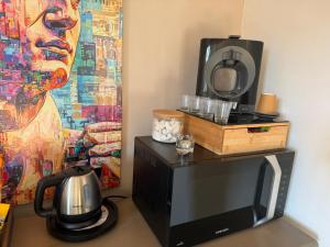 Horizon village des Pennes Mirabeau في لي-بين-ميرابو: ميكروويف وتلفاز مع لوحة على الحائط