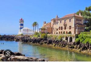 ein Gebäude neben einem Fluss mit einem Leuchtturm in der Unterkunft Home Place Cascais Estoril in Cascais