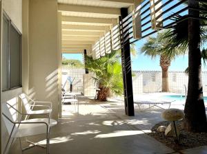 een patio met stoelen, een tafel en een palmboom bij The Gateway Boutique Vacation Rentals in Desert Hot Springs