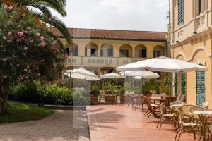 un patio con tavoli, sedie e ombrelloni di Homiday - Villa Rosella a Roseto degli Abruzzi