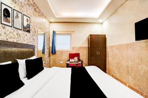 a bedroom with a large bed and a red chair at Collection O Kalka Ji Formerly Hotel Gera in New Delhi