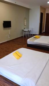 due letti in una stanza con una TV a parete di Hayyan Homestay a Kampong Tangihan