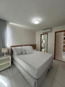 a bedroom with a large white bed with white pillows at Flat Resort ILOA in Barra de São Miguel
