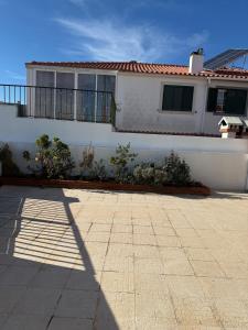ein weißes Haus mit einem Zaun und einer Terrasse in der Unterkunft Casa Almoinha in Sesimbra