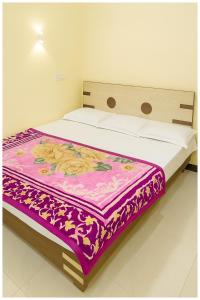 a bed in a room with a blanket on it at Hotel Premium IN Tulsi GH Near Shri Mahakaleshwar Jyotirlinga Temple - Fully Air Air Conditioning Rooms - Prime Location in Ujjain