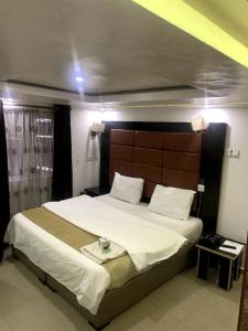 a bedroom with a large bed with a wooden headboard at 111Suites&Lounge in Aba +6 photos