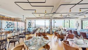 un restaurante con mesas, sillas y ventanas en Radisson Hotel Shimla, en Shimla