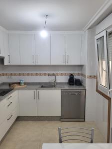 eine Küche mit weißen Schränken, einer Spüle und einem Geschirrspüler in der Unterkunft Piso nuevo y acogedor! in O Porriño + 14 Fotos