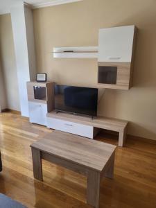 ein Wohnzimmer mit einem TV und einem Holztisch in der Unterkunft Piso nuevo y acogedor! in O Porriño