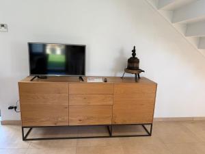 a wooden dresser with a tv on top of it at Le Pressoir, maison au calme, jardin, terrasse, 3 chambres, 2 sdb, 2 WC, proche Bayeux et Arromanches au coeur des plages du débarquement in Longues-sur-Mer