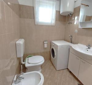 a bathroom with a white toilet and a sink at Apartments Dara in Umag
