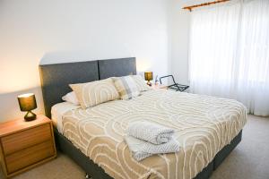a bedroom with a large bed with a wooden nightstand and a window at Griffith Prestige Apartment in Griffith