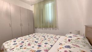 a bedroom with a bed with a floral comforter and a window at Apartments Dara in Umag
