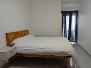 a bedroom with a bed with a wooden frame and a window at Spring Cottage in Walvis Bay