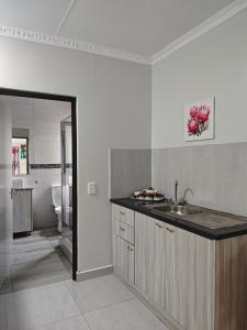 a white kitchen with a sink and a bathroom at Spring Cottage in Walvis Bay
