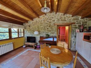 Un comedor con una mesa y una pared de piedra. en Casa Laudina y Armando, en Brañella