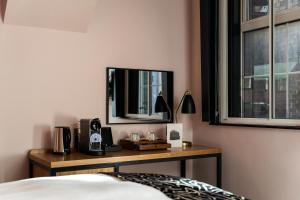 a bedroom with a desk with a television and a bed at The Wellington Hotel in London